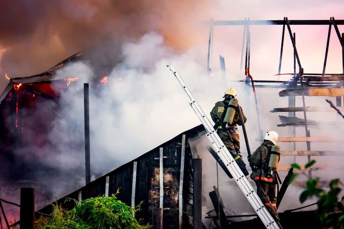 firefighters-battle-a-wildfire-against-a-background-of-thick-white-smoke-firefighters-on-the-stairs-extinguish-the-roof-of-a-private-house-or-barn_431724-1909